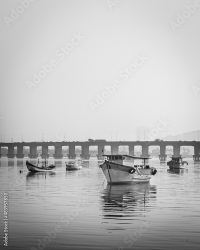 Fototapeta Naklejka Na Ścianę i Meble -  Barcos de pesca ancorados no mar e ao fundo uma ponte 