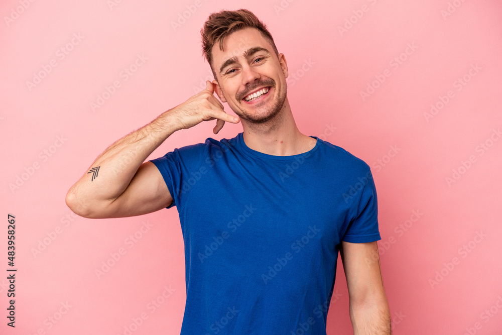 Young caucasian man isolated on pink background showing a mobile phone call gesture with fingers. Young caucasian man isolated on pink background showing a mobile phone call gesture with fingers.