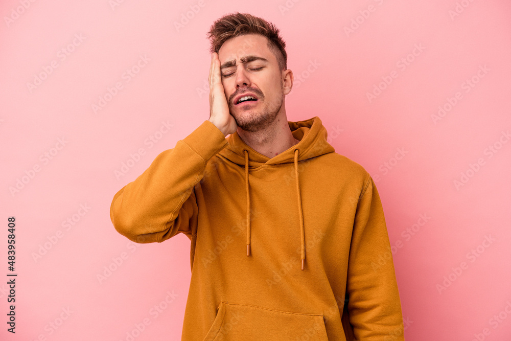 Fototapeta premium Young caucasian man isolated on pink background tired and very sleepy keeping hand on head.