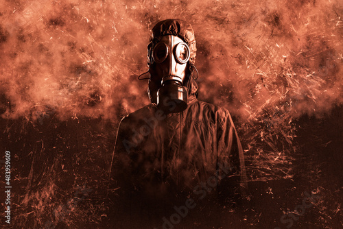 grown male stalker. He is dressed in a protective jacket with a hood, a gas mask. He looks into the camera. On a grunge brown background. Poster apocalyptic photo