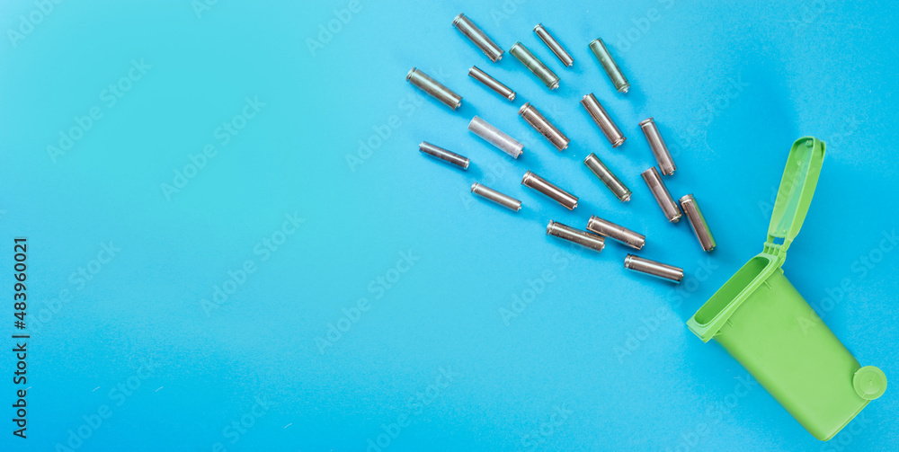 Batteries and a green plastic container on a blue background. View from above. Recycling. Ecological concept Batteries and a green plastic container on a blue background. View from above. Recycling. Ecological concept