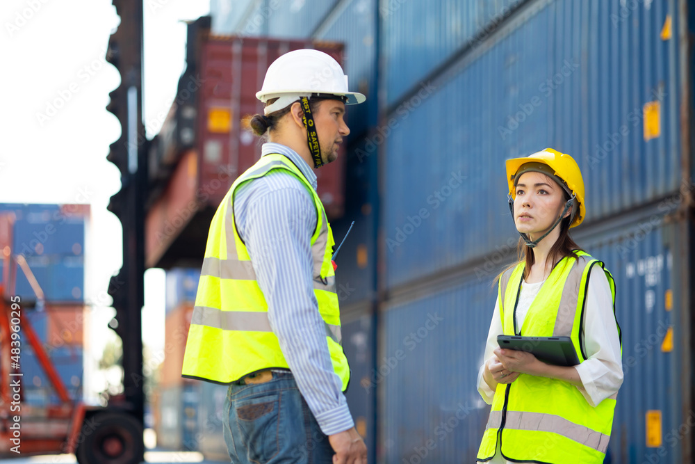 Man manager and woman Supervisor dock cargo checking and control loading Containers box at container yard port of import and export goods. Unity and teamwork concept Man manager and woman Supervisor dock cargo checking and control loading Containers box at container yard port of import and export goods. Unity and teamwork concept