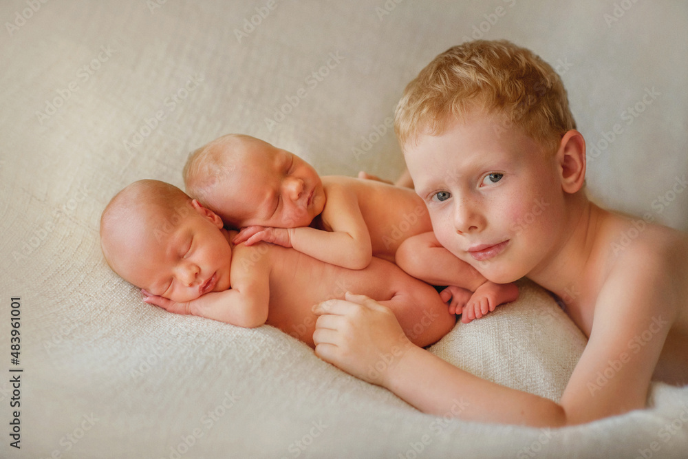 Twins. The large family. Brothers. Elder brother and younger brothers. Newborn babies. Boys. Newborn twins in the crib. Happy big brother. Happy family. Sweet babies. Older brother hugging younger new Twins. The large family. Brothers. Elder brother and younger brothers. Newborn babies. Boys. Newborn twins in the crib. Happy big brother. Happy family. Sweet babies. Older brother hugging younger new