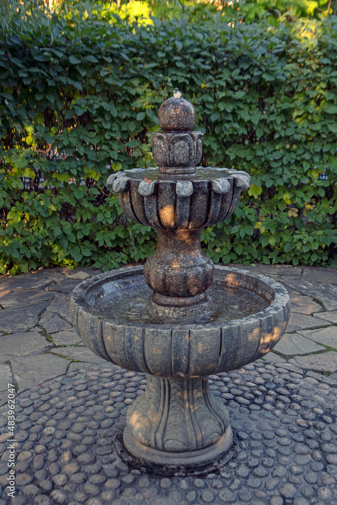 Fragment of landscape design of the park. Garden fountain against the background of green bushes. Fragment of landscape design of the park. Garden fountain against the background of green bushes.