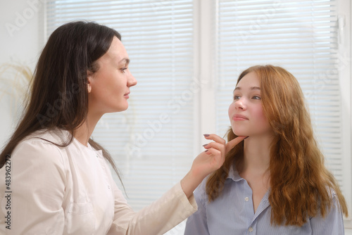 A young red-haired beautiful girl undergoes a medical examination in a cosmetology clinic. A female dermatologist consultation.