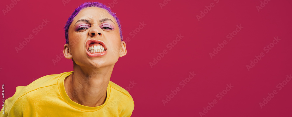 Quirky young woman making a face in a studio - obrazy, fototapety, plakaty 