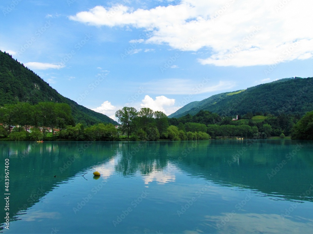 Lake at Most na Soci in Littoral region of Slovenia with forest covered hills behind and a reflection of the hills in the lake