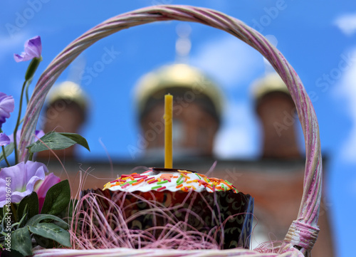 A cake with a candle on the background of the domes of an Orthodox church, a symbol of Easter