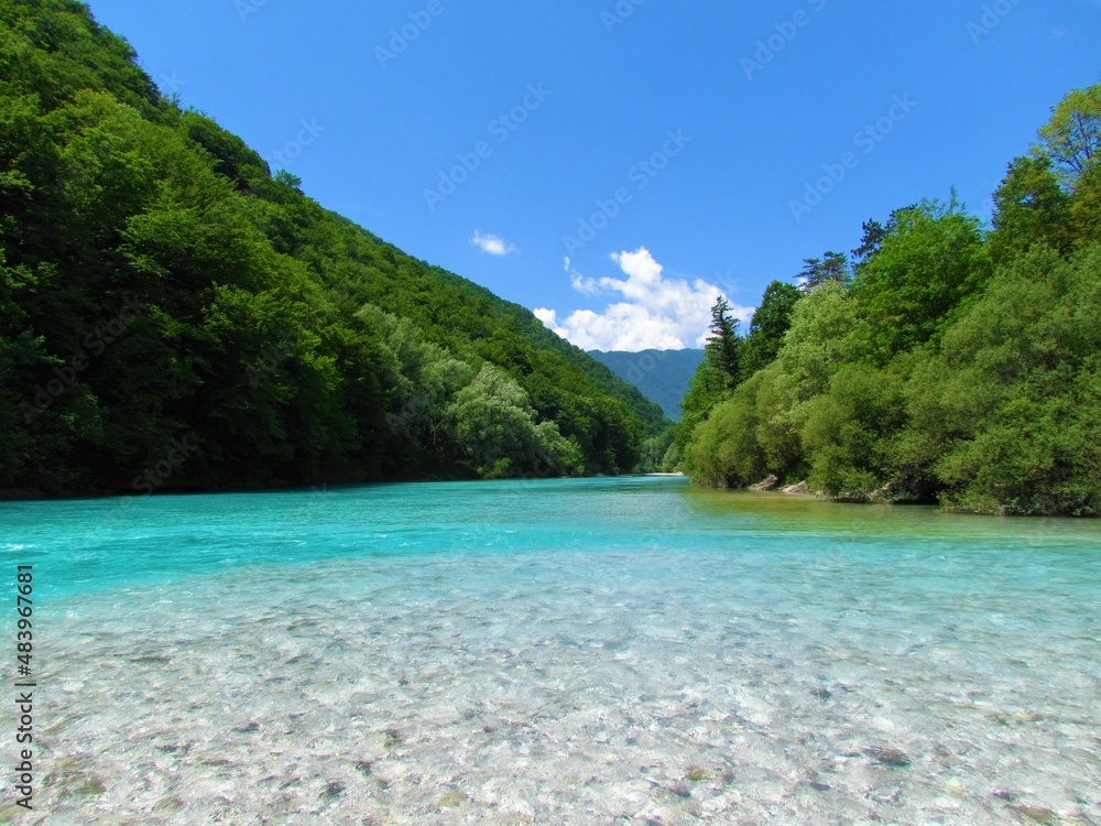 Soca river in surrounded by forest covered slopes in summer in Littoral region of Slovenia