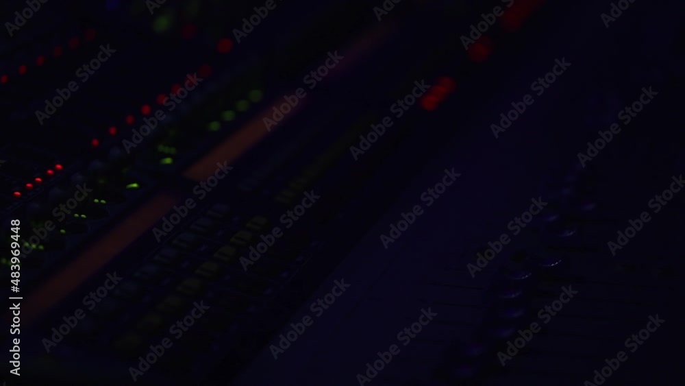 The red signal lights of the sound engineer's console flash in the dark, the sound console is illuminated by blue light from the stage. The red signal lights of the sound engineer's console flash in the dark, the sound console is illuminated by blue light from the stage.