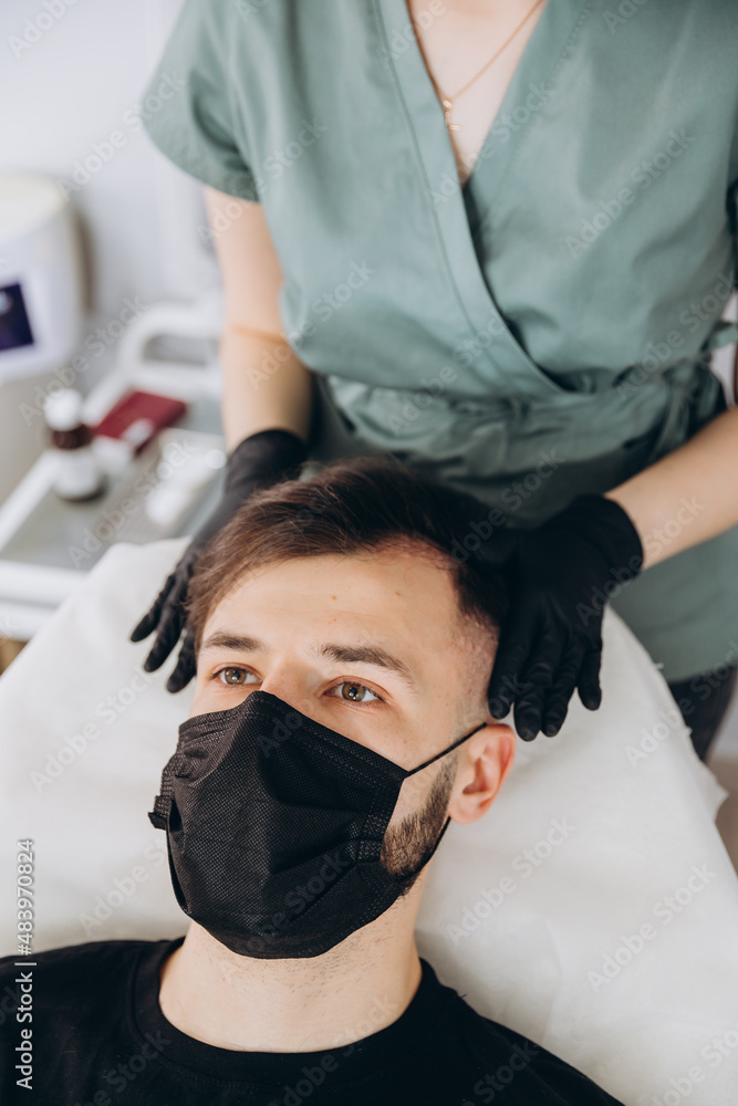 Mesotherapy procedure. A cosmetologist performs a mesotherapy procedure on the head of a young man. Hair strengthening and growth. Mesotherapy procedure. A cosmetologist performs a mesotherapy procedure on the head of a young man. Hair strengthening and growth.