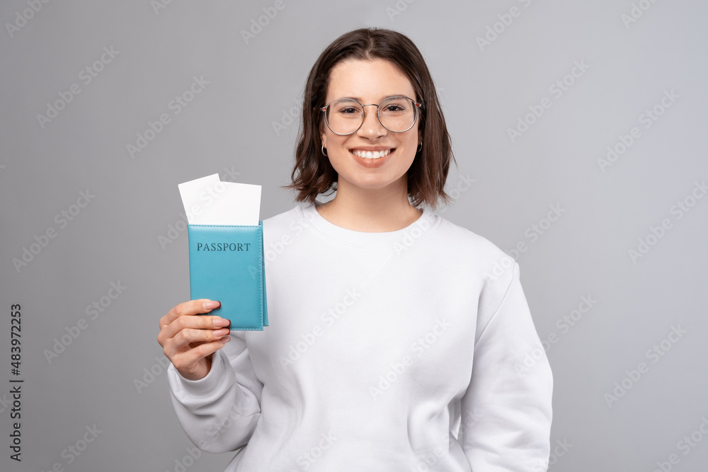 Joyful young woman smiling and holding passport and airplane tickets. Joyful young woman smiling and holding passport and airplane tickets.