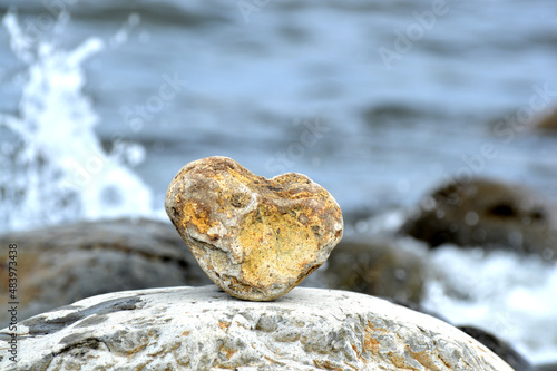 Heart shape stone against background of beach. Summer sunny day. Love, wedding and Valentine day concept. Finding beautiful and interesting stones. Beach vacation. 