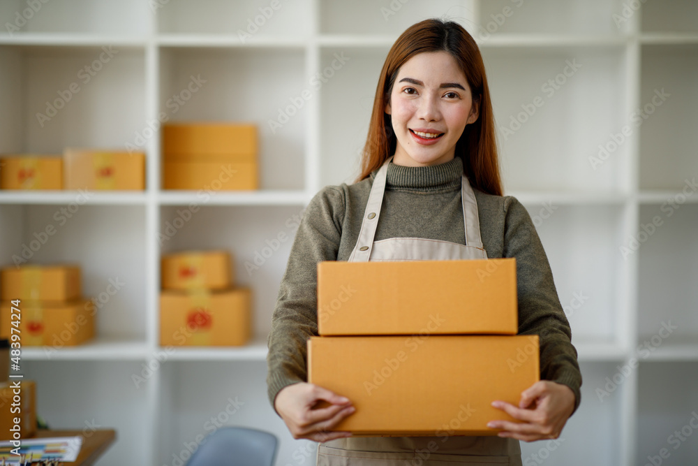 Startup SME small business entrepreneur SME or freelance Asian woman using a laptop with box, Young success Asian woman with her hand lift up, online marketing packaging box and delivery, SME concept. Startup SME small business entrepreneur SME or freelance Asian woman using a laptop with box, Young success Asian woman with her hand lift up, online marketing packaging box and delivery, SME concept.
