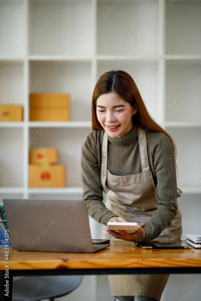 Startup SME small business entrepreneur SME or freelance Asian woman using a laptop with box, Young success Asian woman with her hand lift up, online marketing packaging box and delivery, SME concept. Startup SME small business entrepreneur SME or freelance Asian woman using a laptop with box, Young success Asian woman with her hand lift up, online marketing packaging box and delivery, SME concept.