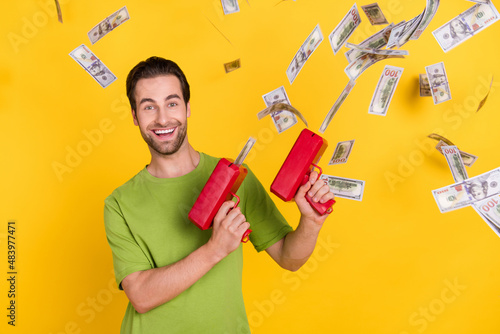 Canvas-taulu Photo of joyful beard millennial guy with money gun wear green t-shirt isolated