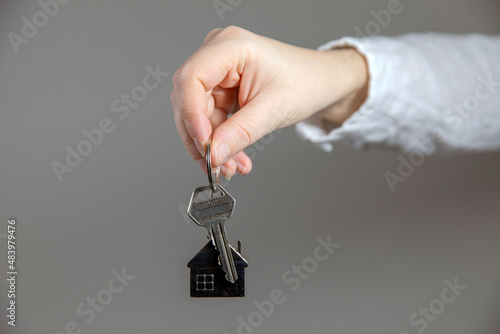 Real estate agent with house model and keys, selling house,property owner mortgage concept with copy space on gray background