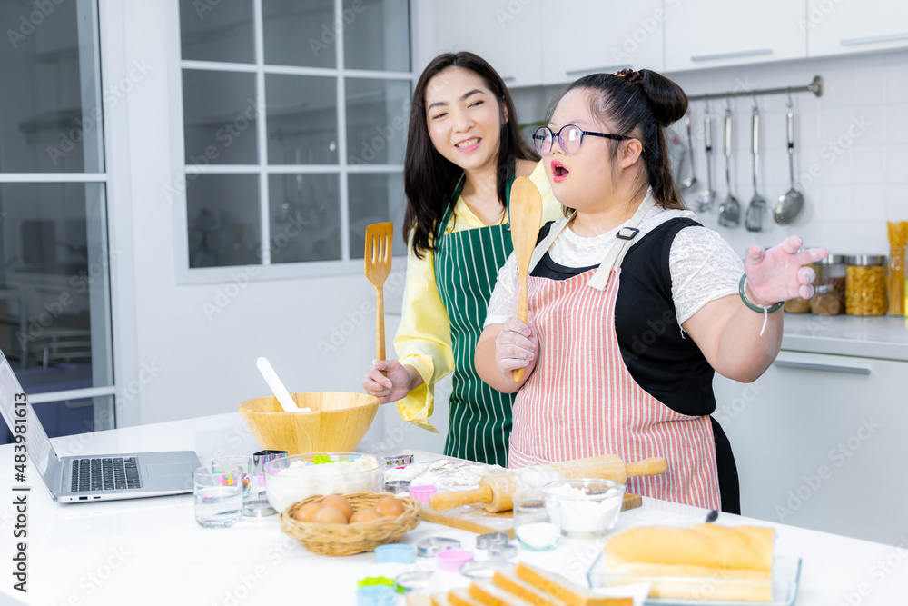 asian Down syndrome girl cooking with mom Smile. The concept is mental health, physical growth. Brain growth, learning, family love, intelligence, cooking
