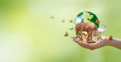 Earth Day or World Wildlife Day concept. Save our planet, protect green nature and endangered species, biological diversity theme. Group of wild animals and  flock of butterflies with globe in hand.