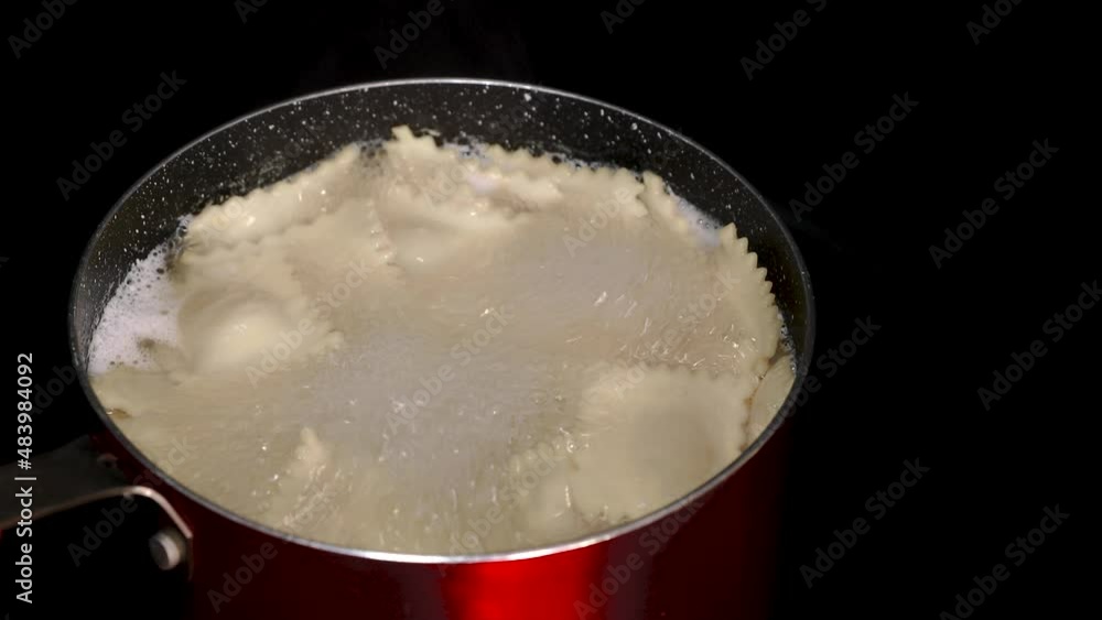 Slow slide along ravioli cooked in a red metal pot on black background Slow slide along ravioli cooked in a red metal pot on black background