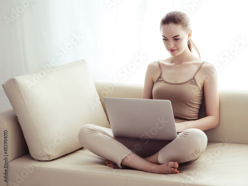 Woman with laptop on sofa working home alone lifestyle.