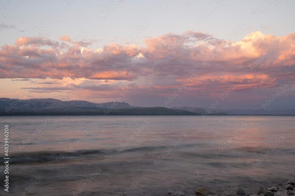Long exposure shot of Nahuel Huapi lake and the Andes mountains in the background, at sunset. Beautiful blurred water effect, the rocky shore and dusk colors in the sky. Long exposure shot of Nahuel Huapi lake and the Andes mountains in the background, at sunset. Beautiful blurred water effect, the rocky shore and dusk colors in the sky.