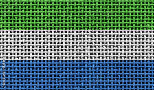 Sierra Leone flag on the surface of a metal lattice. 3D image