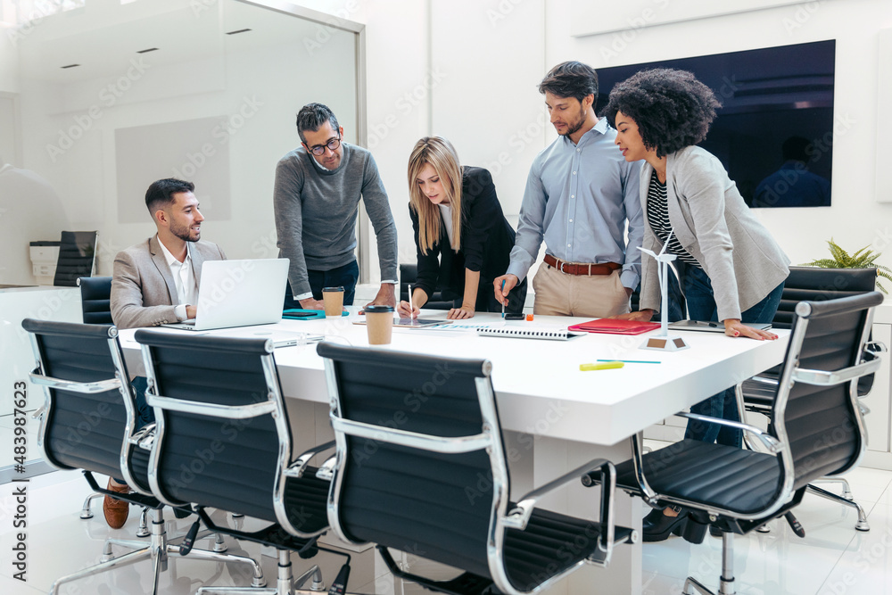 Successful business team standing around computer for presentation of work in a modern startup.