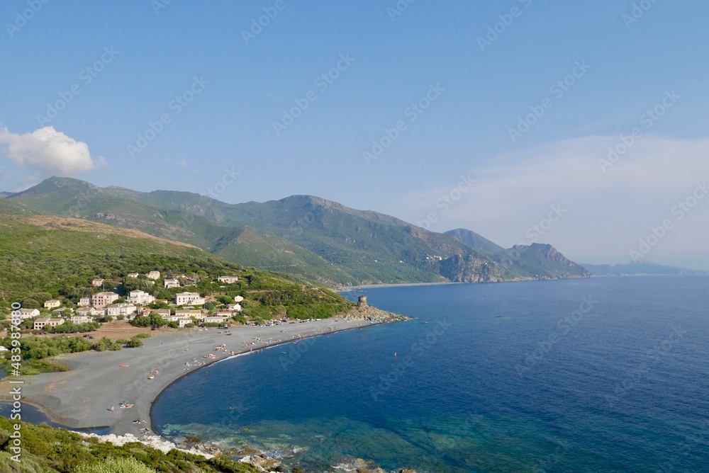 Panoramic view of black pebble beach and Genoese tower of Albo, Cap Corse. Corsica, France.