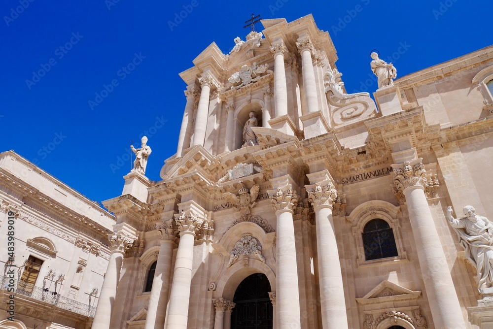 Facade of Baroque cathedral of Syracuse in Ortigia against blue sky. Sicily, Italy.
