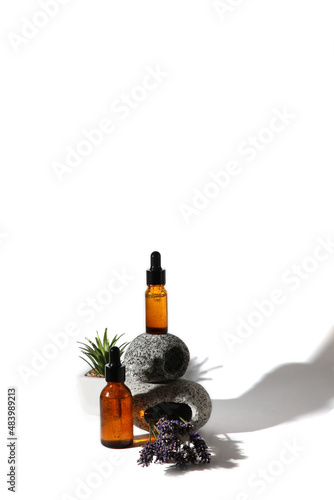 Fototapeta Naklejka Na Ścianę i Meble -  Serum for the face on a podium of gray stones on a white isolated background with a bunch of lavender