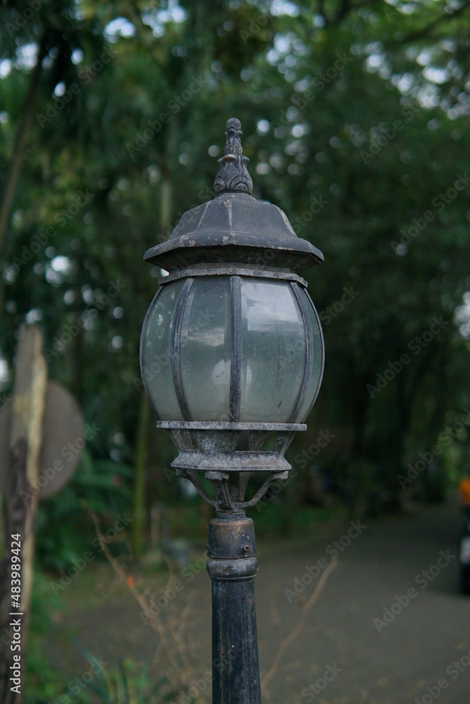 decorative antique style lamp. Old gas lanterns lit in the morning. lamp with green plants. Decorative lanterns in the garden. Retro lantern among on garden background.