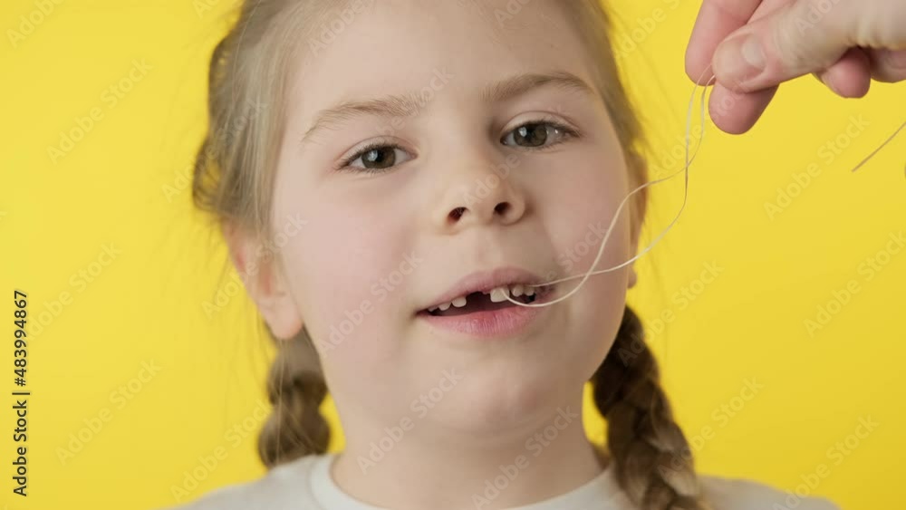 Toothless girl getting ready to pull tooth using thread at yellow ...