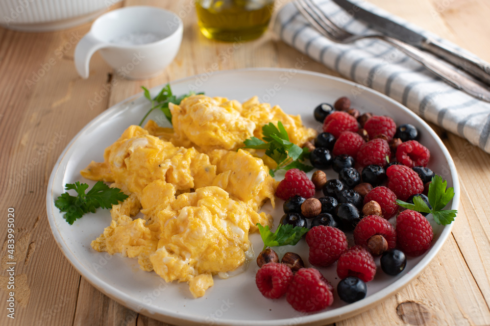 Low carb breakfast plate with scrambled eggs, fresh berries and hazelnuts
