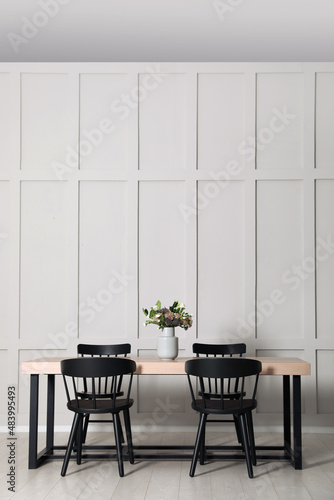 Stylish dining room interior with wooden table and chairs near molding wall, space for text © New Africa
