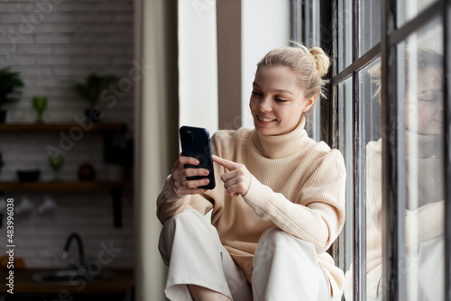 Happy teen girl checking social media holding smartphone at home. Using mobile phone shopping online, ordering delivery