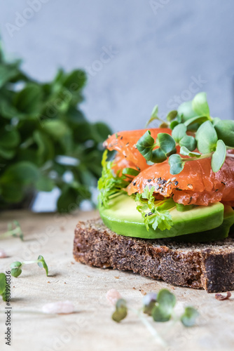 Healthy open sandwich with salmon and avocado and microgreens.