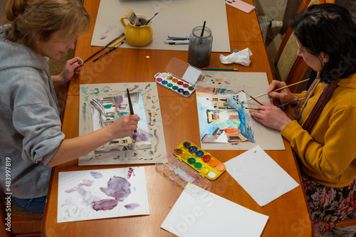 Young women working on watercolor painting of cityscape