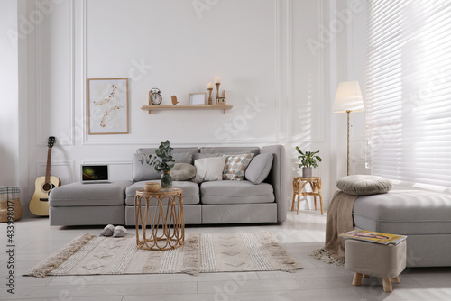 Living room with comfortable grey sofa  ottoman and stylish interior elements near window