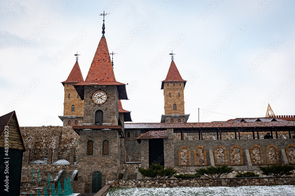 Part of the fortress wall of the castle, with a tower and a large clock tower. Architecture of one of the districts of the Rostov region of the Russian Federation.
