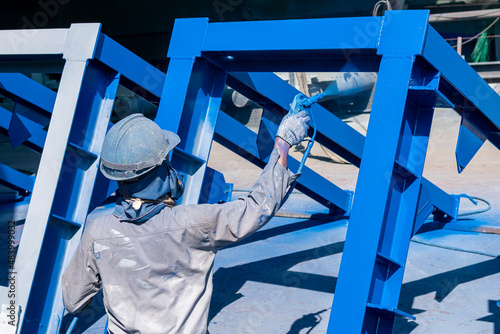 The painter uses a spray gun to paint a steel structure before transportation to the assembly yard.
