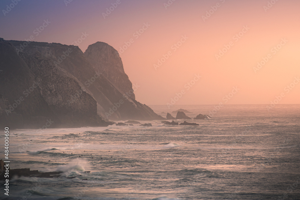 sunset over the ocean with a lighthouse