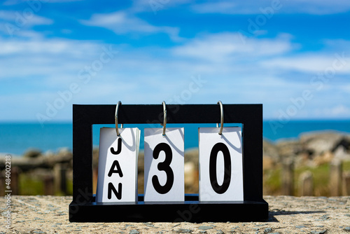 Jan 30 calendar date text on wooden frame with blurred background of ocean