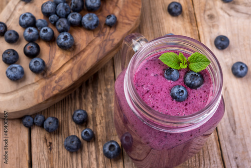 Blueberry cocktail (smothie) in a glass on a rustic wooden background.