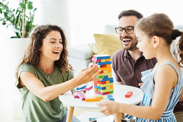 child daughter family happy mother father board game palying playing fun together girl cheerful home