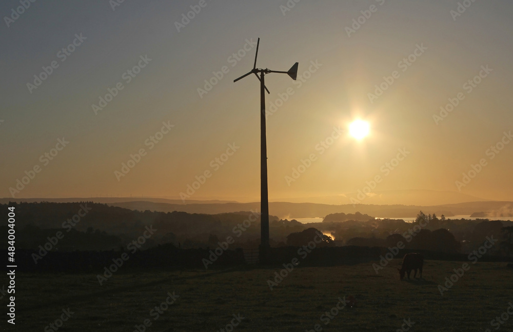 Obraz premium small micro wind turbine generator silhouette at sunrise