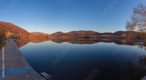 Large autumn panorama of small village and Prosecco Unesco Hills reflected on the waters of lake at sunset. Revine Lakes  Veneto  Italy. Concept about peace and relaxation. Popular travel destination