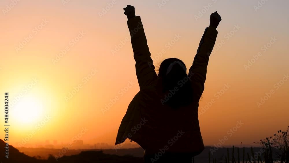 Silhouette of an Indian woman raising her arms in front of the ...