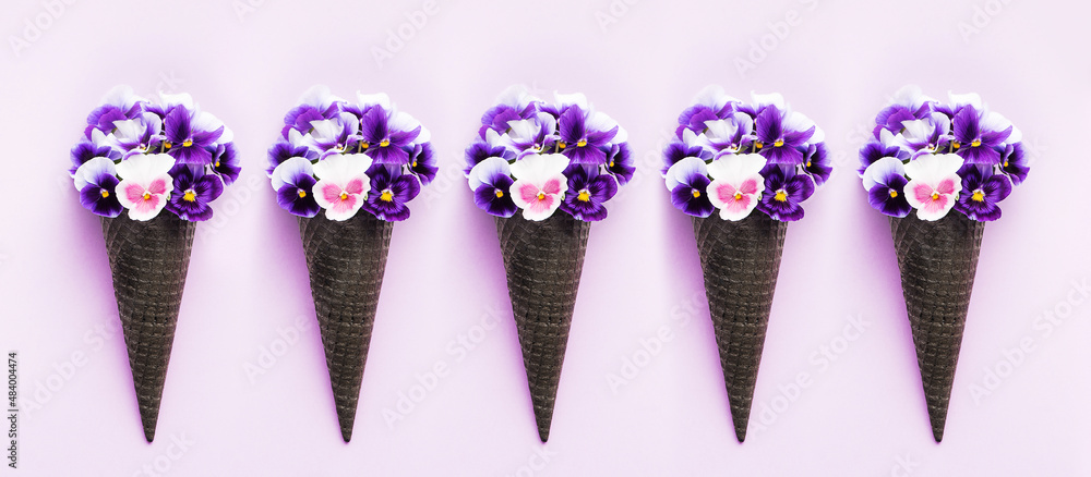 waffle cones with flower bouquet pansies on lilac background. Flat lay, banner, creative concept. waffle cones with flower bouquet pansies on lilac background. Flat lay, banner, creative concept.