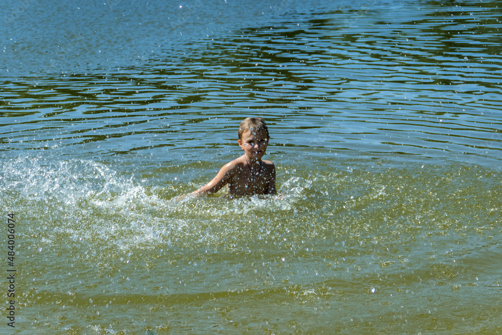 a boy bathes in a forest lake, jumps, in the water
